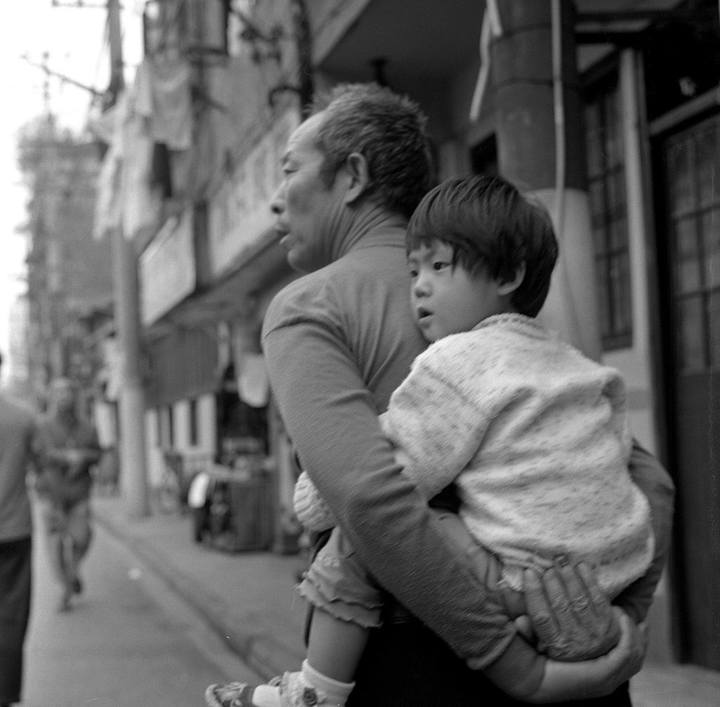 Grandfather gives piggyback to his granddaughter in Shanghai street