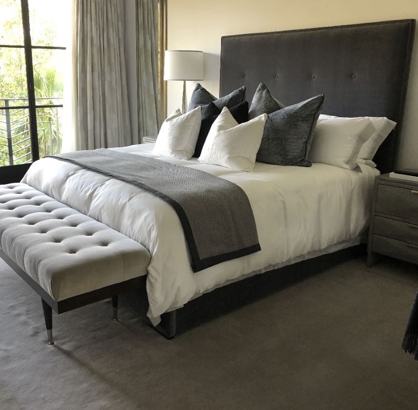 Transitional bedroom with tufted headboard, neutral bedding, and bench, designed by Solo Home Decor.