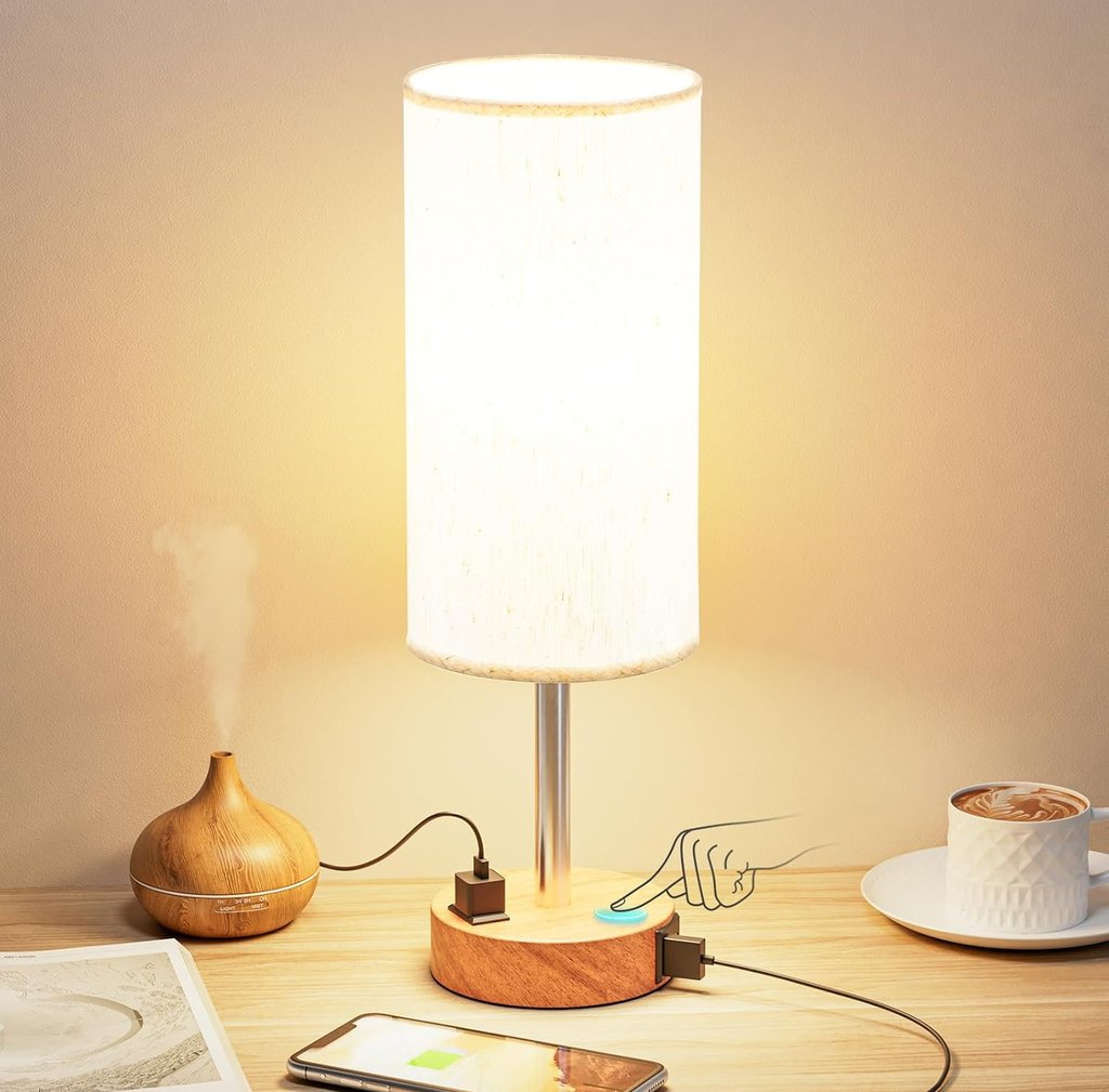 Modern touch control table lamp with wooden base, USB charging ports, and fabric shade on a desk.