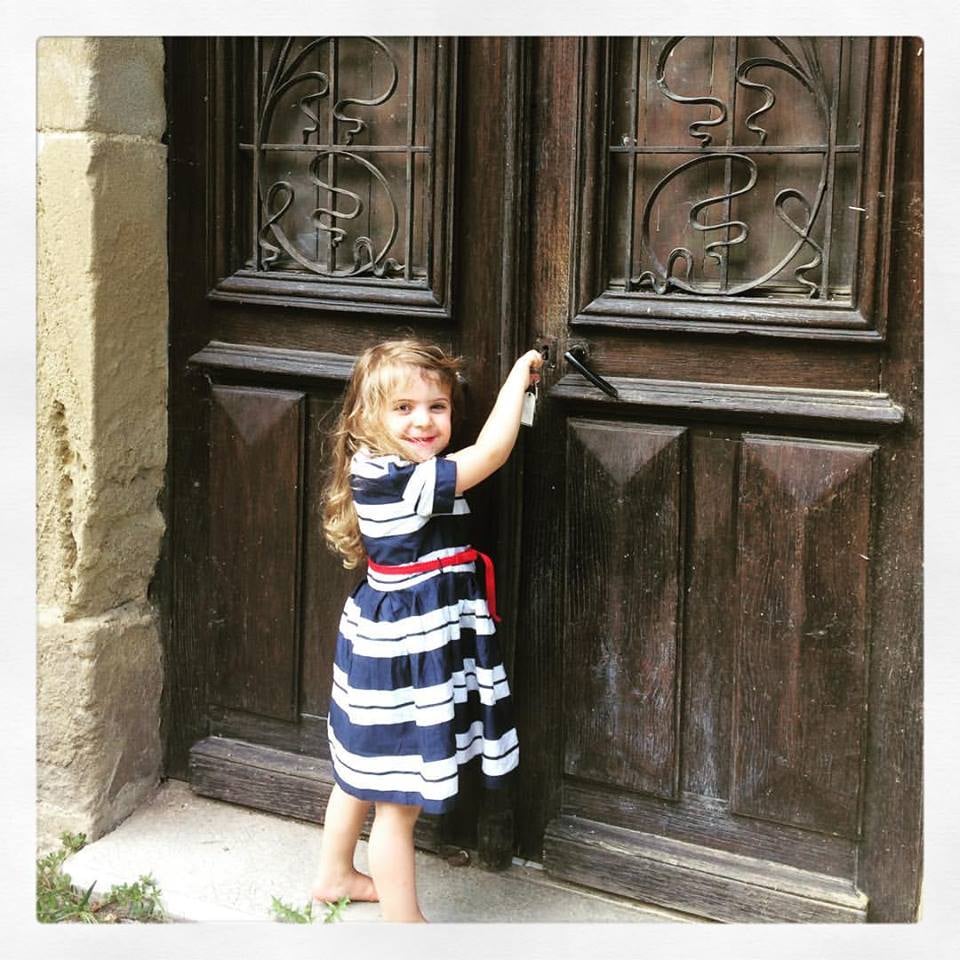 A young girl knocking at an old door
