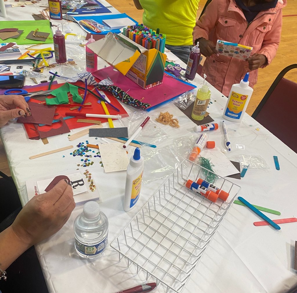 a group of people sitting at a table with craft supplies making a creative journal