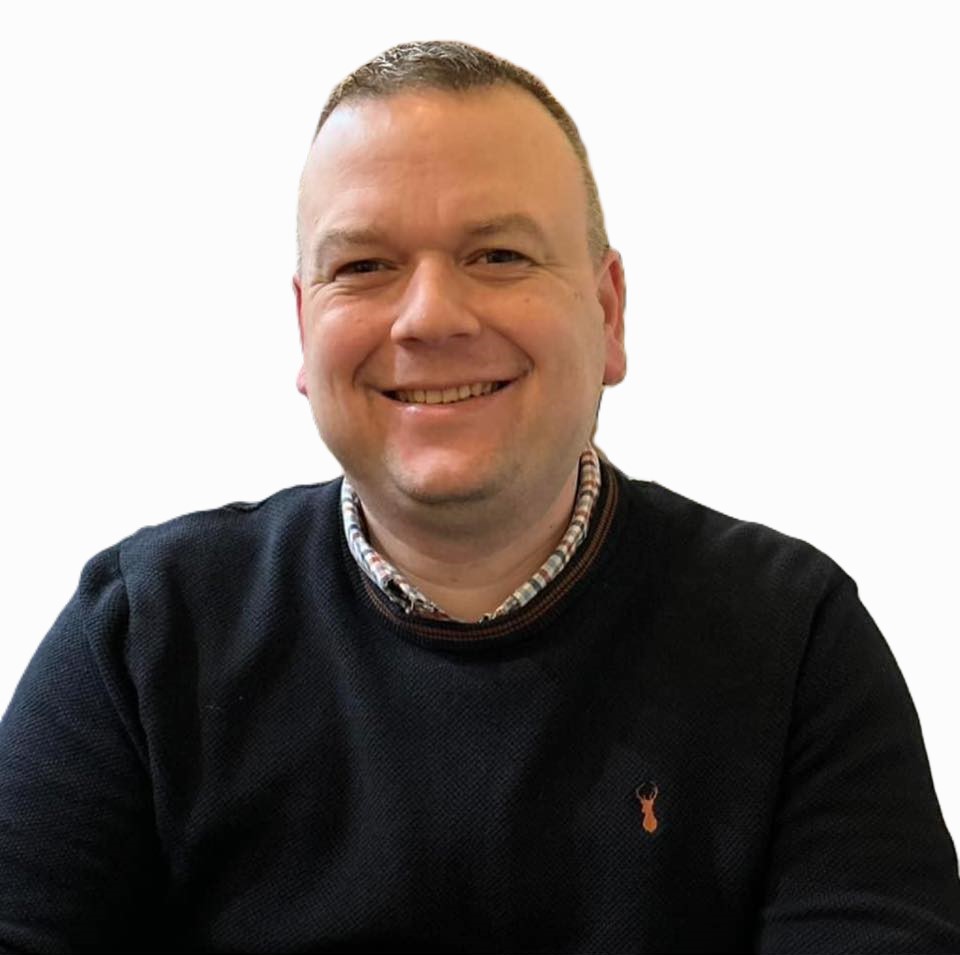 Smiling professional man in a black sweater and collared shirt for a business headshot.