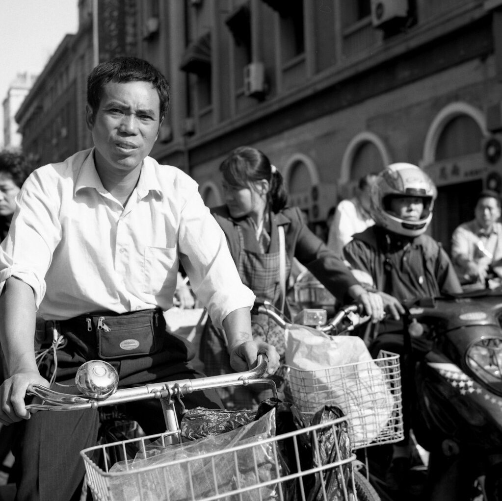 Man on bicycle waits at traffic lights in Shanghai in morning rush hour