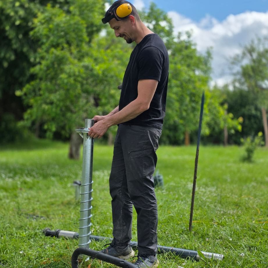 Ouvrier qui pose une vis de fondation pour un abri de jardin