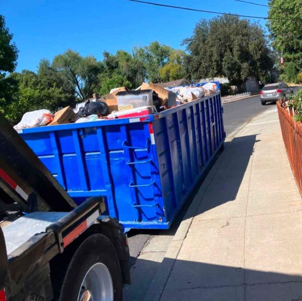 a dumpster truck with a large amount of trash in the back of it