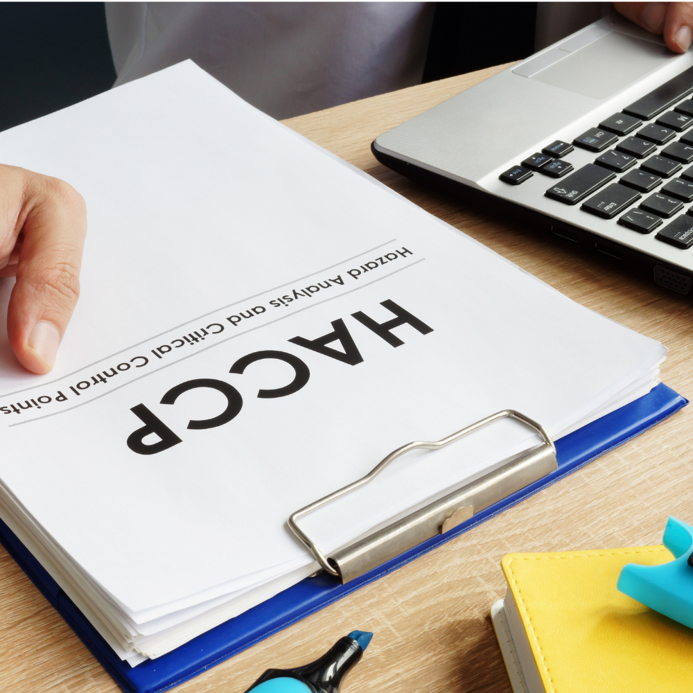 A person reviews a HACCP hazard analysis and critical control points document on a blue clipboard.