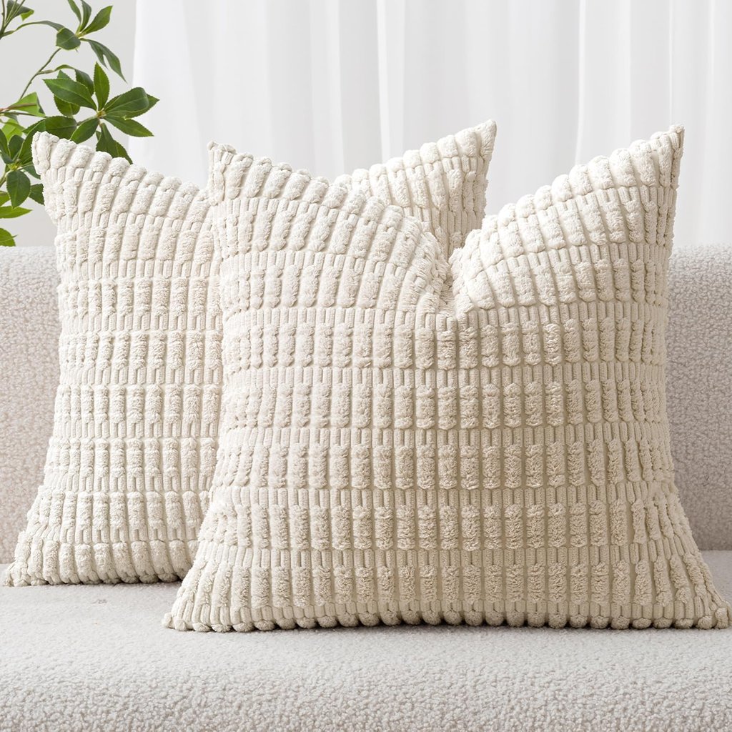 Two cream-colored corduroy textured throw pillows arranged on a soft white boucle sofa.