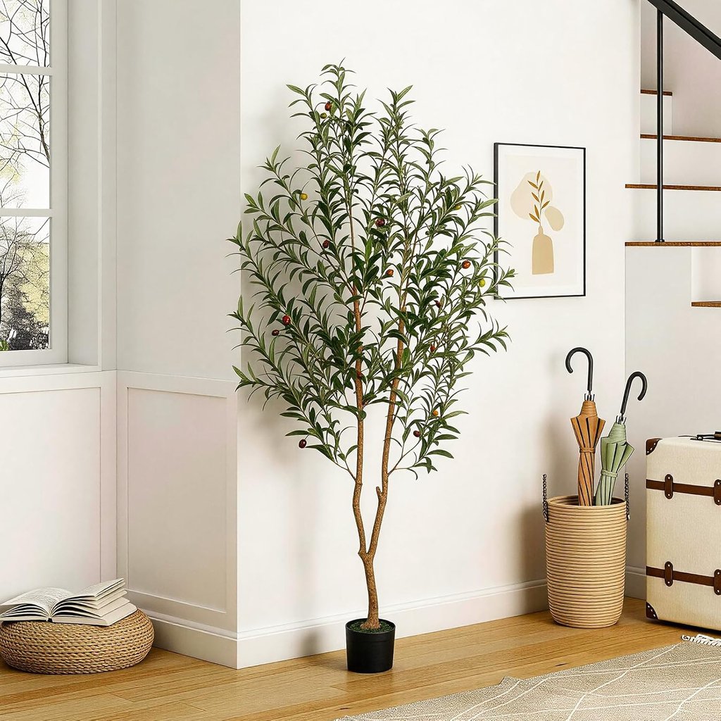 Tall artificial olive tree in a black pot decorating a bright modern living room corner.