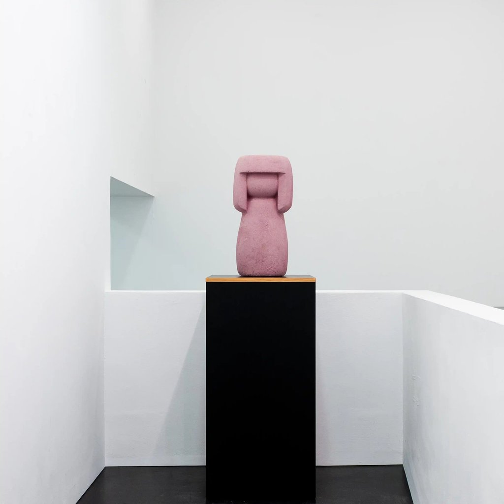 Eine rosa rötliche Kokeshi auf einem Podest im Museum