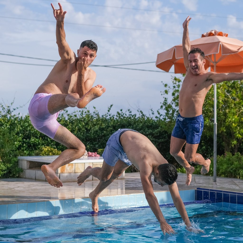 grupo de amigos se divertindo ao pular na piscina durante momento de lazer ao ar livre