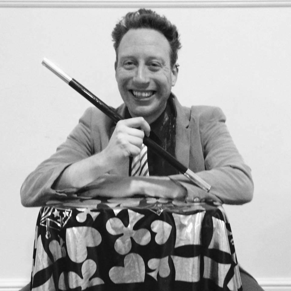 a man in a suit and tie is smiling and holding a knife and knife