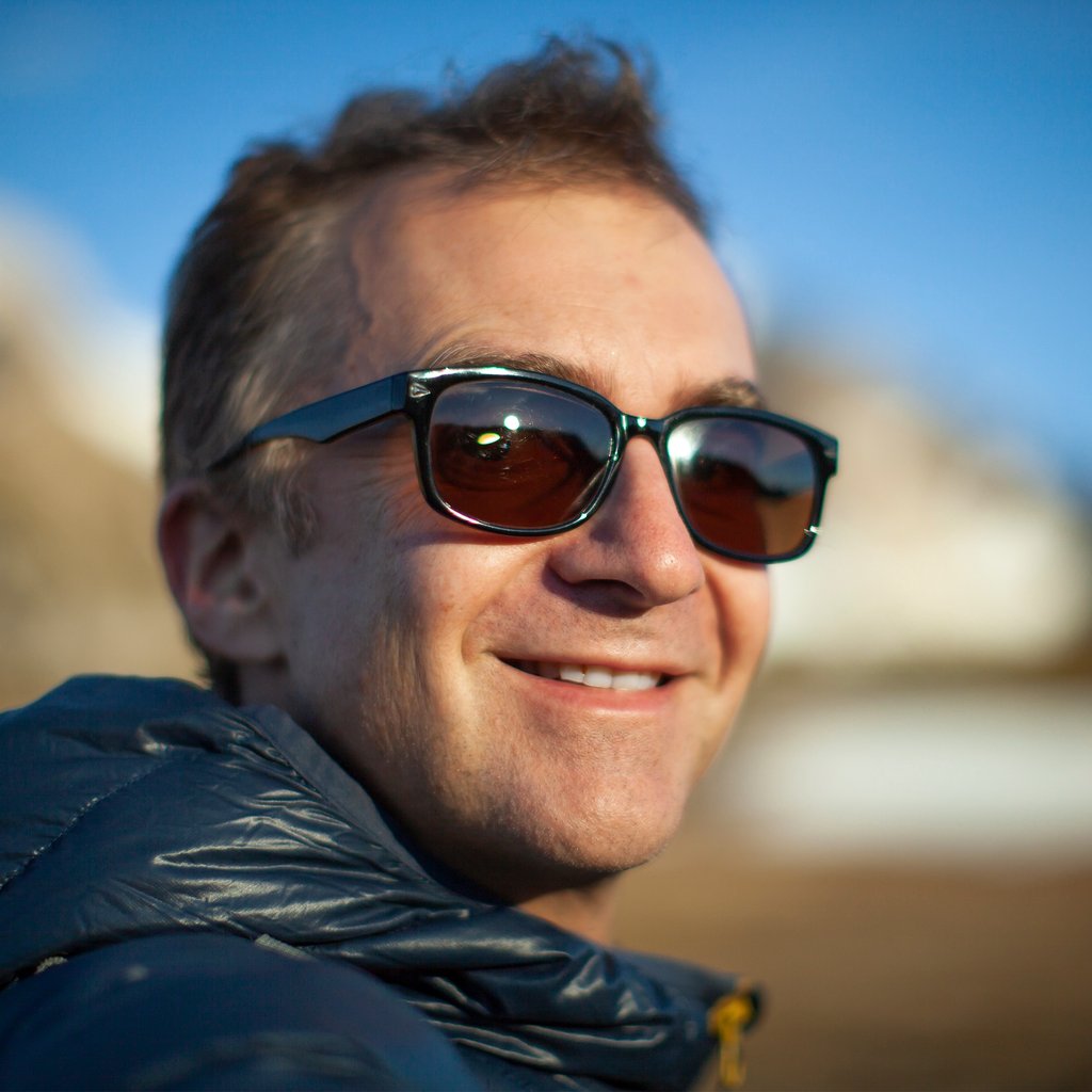 a man in sunglasses and a jacket is smiling