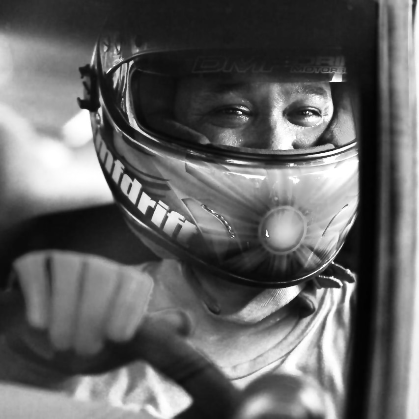 Close-up of a race car driver with a race helmet on inside a car