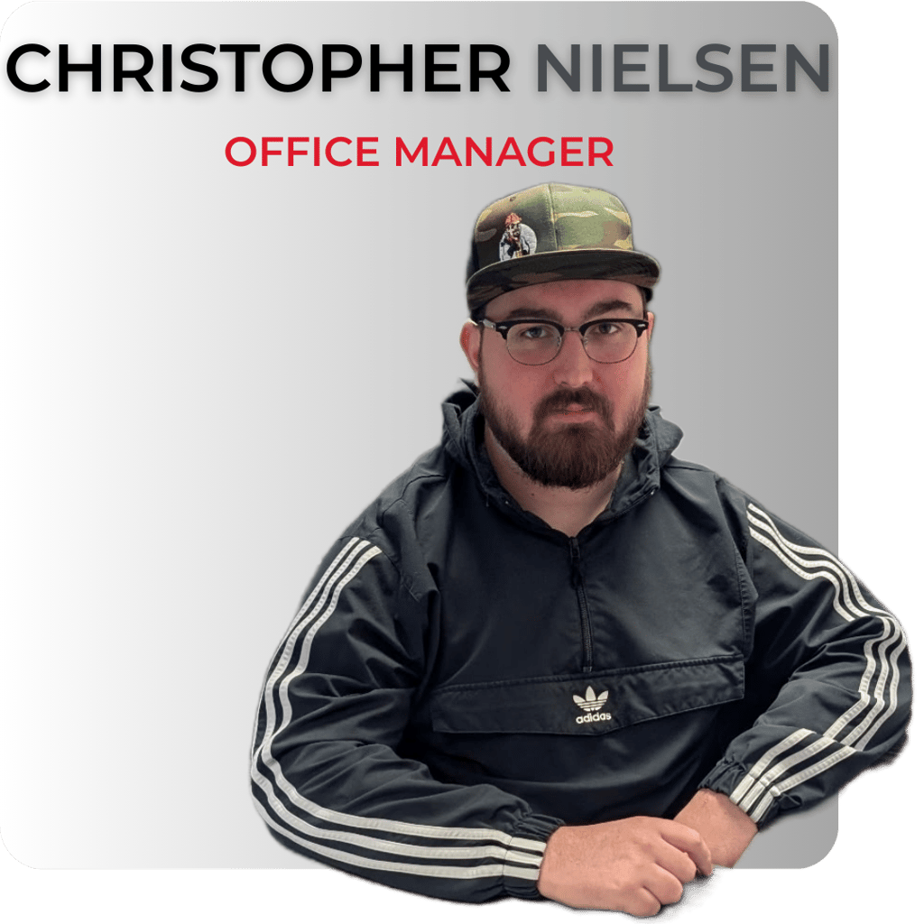 Professional headshot of Office Manager Christopher Nielsen wearing a camo hat and glasses.