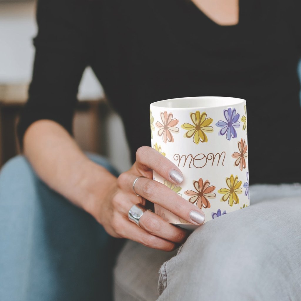 A woman holding a floral mug with 'mom' written on it, perfect for Mother's Day gifts by Mara Branco
