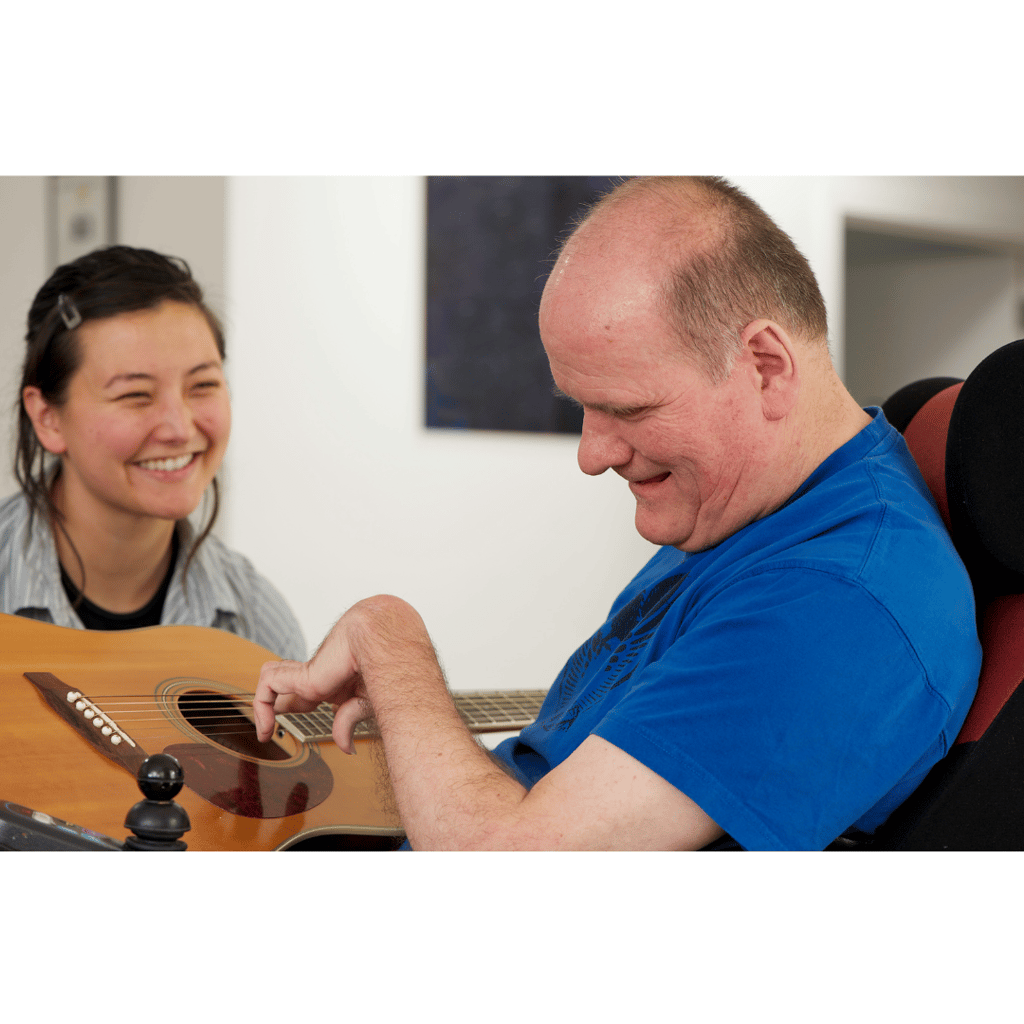 A disabled adult male learning to play the guitar