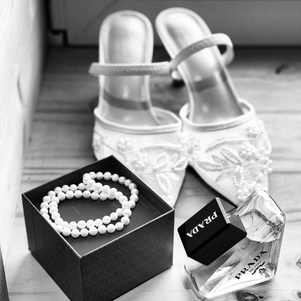 Des accessoires de mariée élégants, notamment un parfum Prada, un collier de perles et des chaussure
