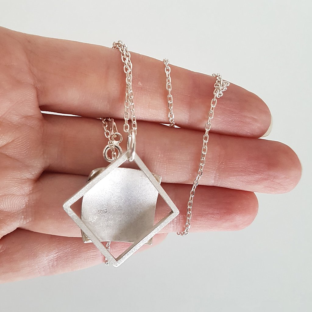 Hand holding a handmade 925 sterling silver geometric square pendant necklace with a minimalist link chain.