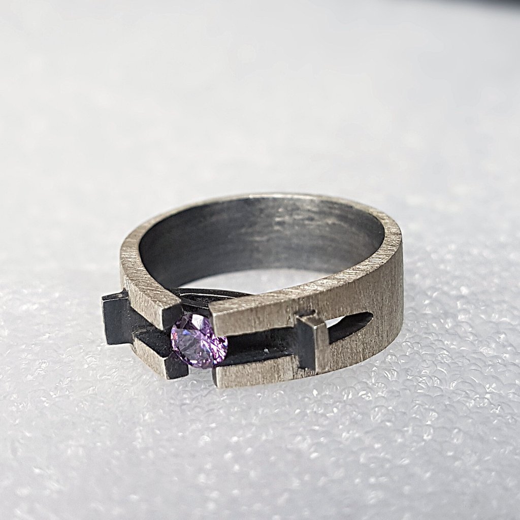a ring with a purple stone ring on top of a white surface