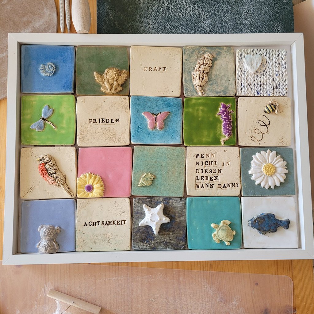 Handmade ceramic tiles with 3D animal and nature motifs in a white display frame.