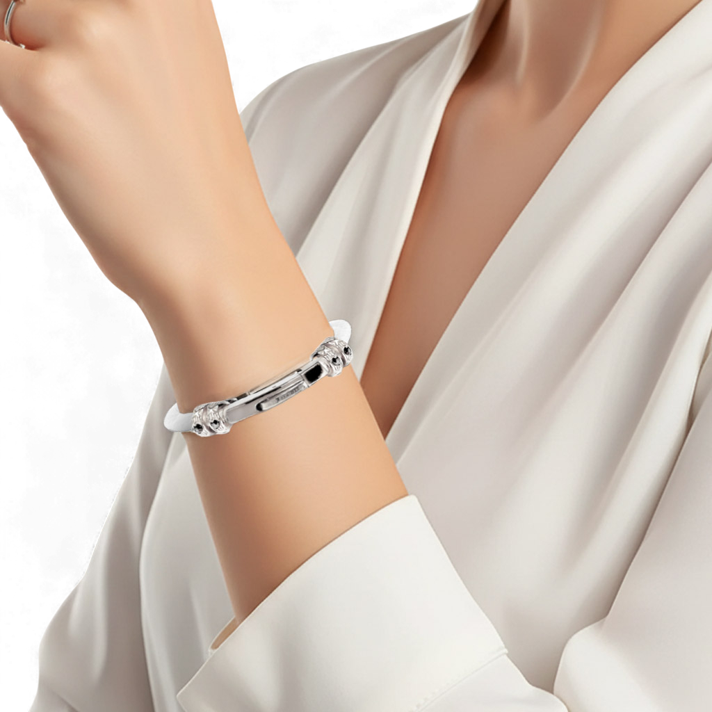 A woman wearing an elegant silver bangle bracelet with intricate clasp detailing on her wrist.