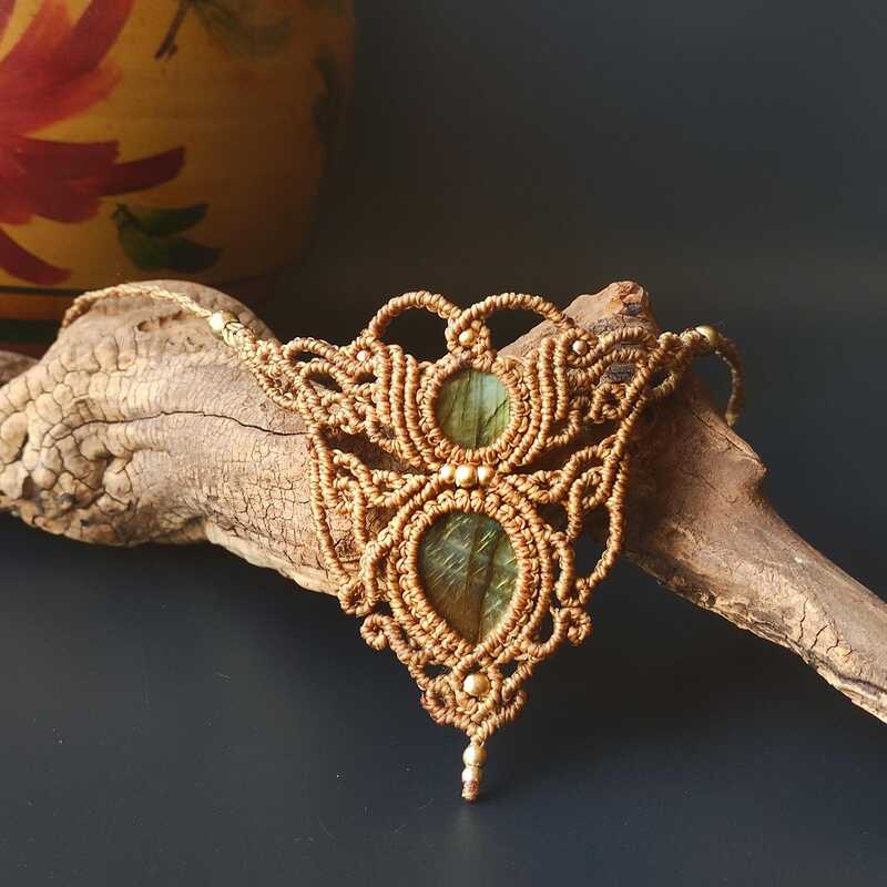 Collar de macramé hecho a mano con piedras de labradorita verde sobre un trozo de madera