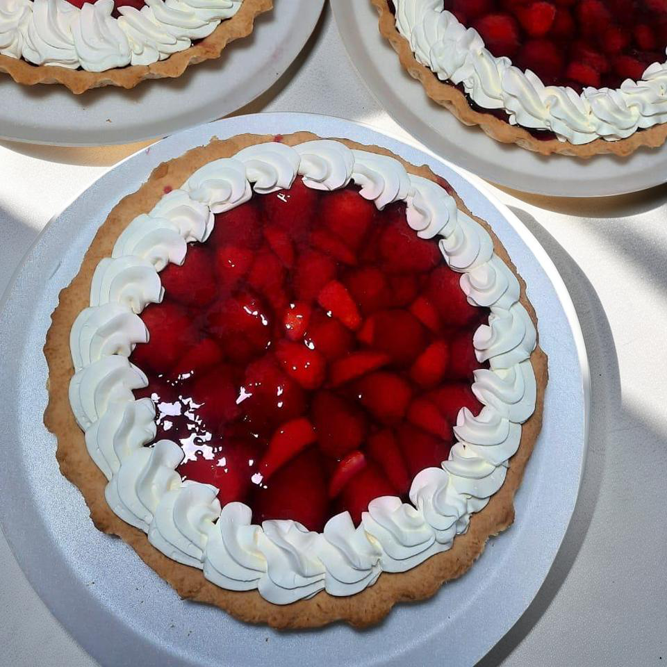 Tarta de fresa fresca con glaseado y glaseado de crema batida en un plato blanco.