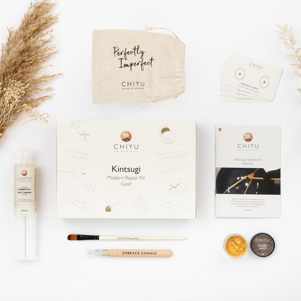 Kintsugi repair kit with gold powder, tools, and manual for mindful ceramic restoration at home.