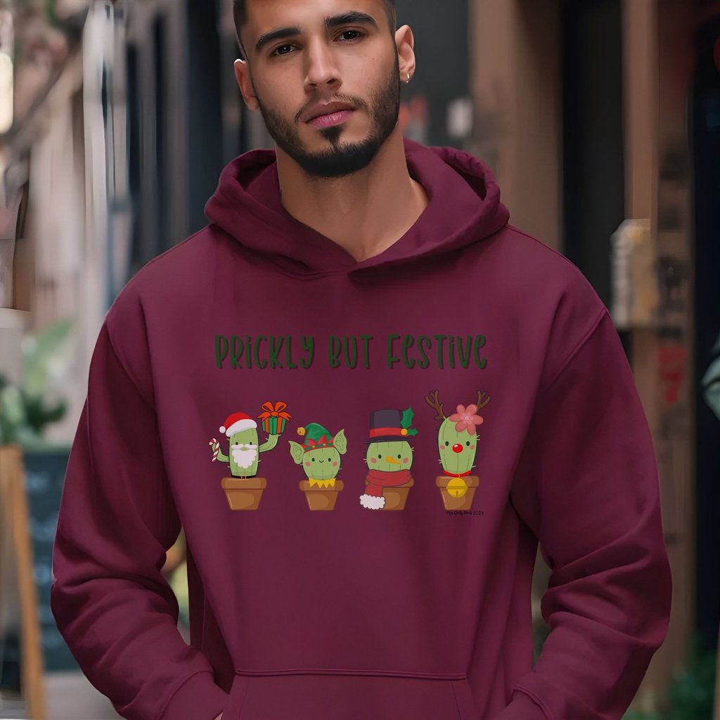 Man wearing maroon hoodie with “Prickly but Festive” cactus design — Christmas hoodie for plant lovers by Miss Chatty Plants