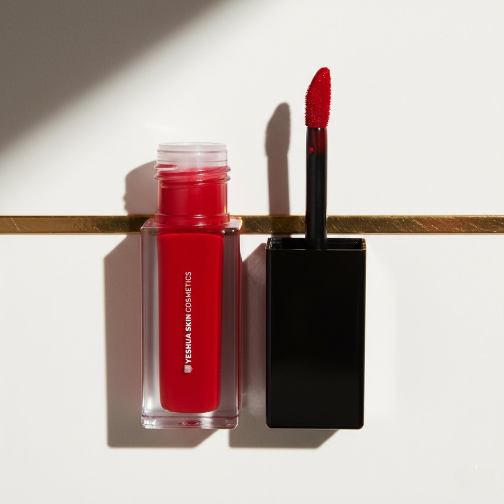 YESHUA Skin Cosmetics vibrant red lip stain bottle with an open applicator brush on a white surface.