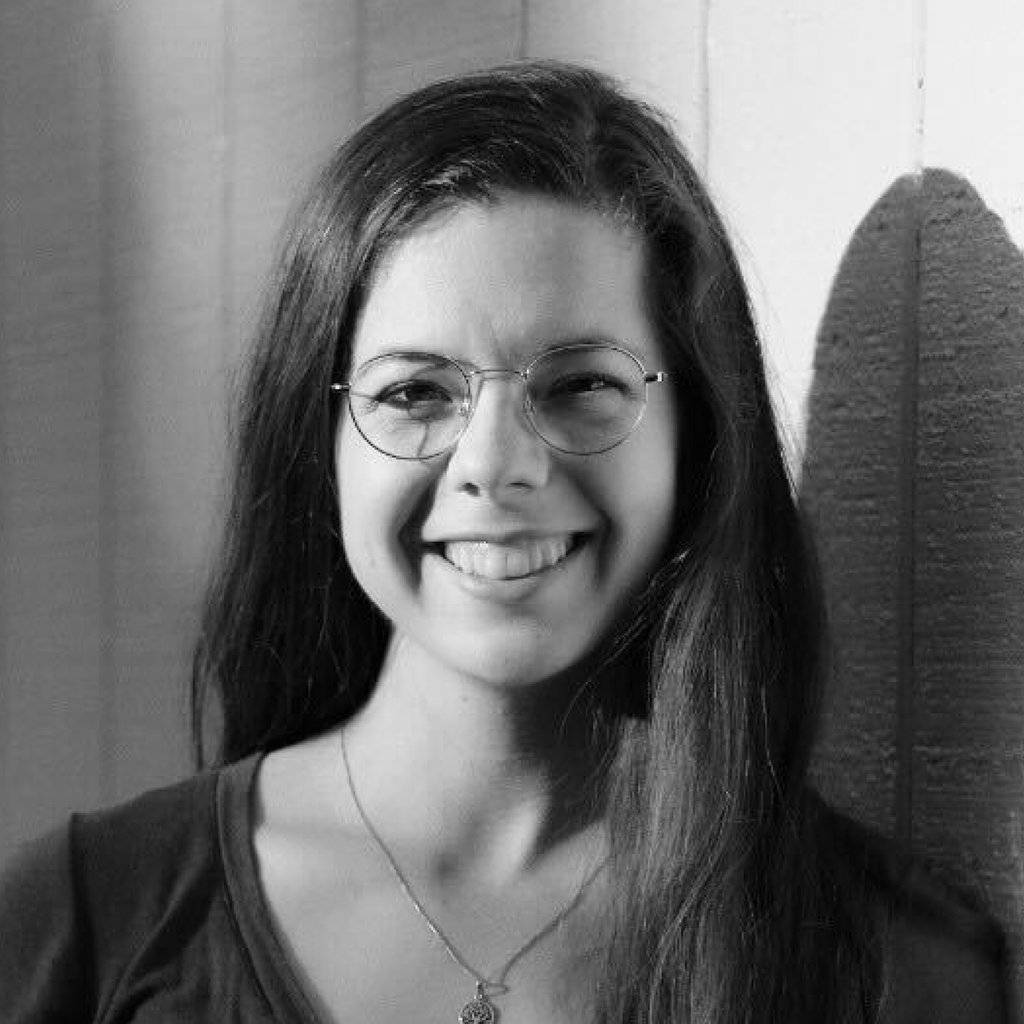 April Reissmann, a woman with glasses, wearing a v neck shirt and a necklace 
