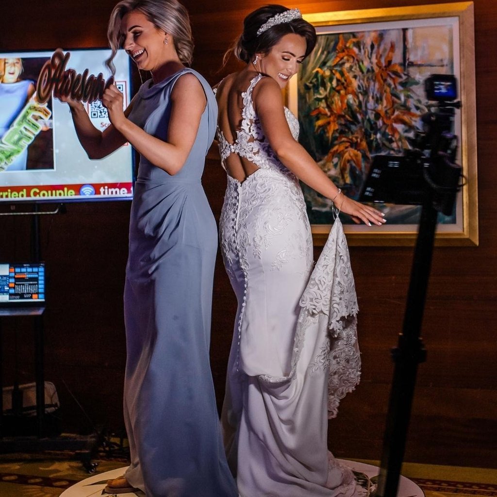 Bride and Maid of Honor standing on a 360 video booth