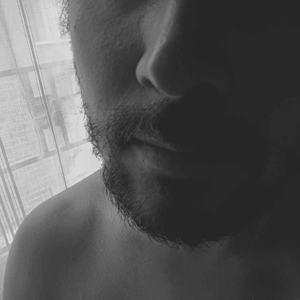Primer plano de rostro masculino con barba en blanco y negro.