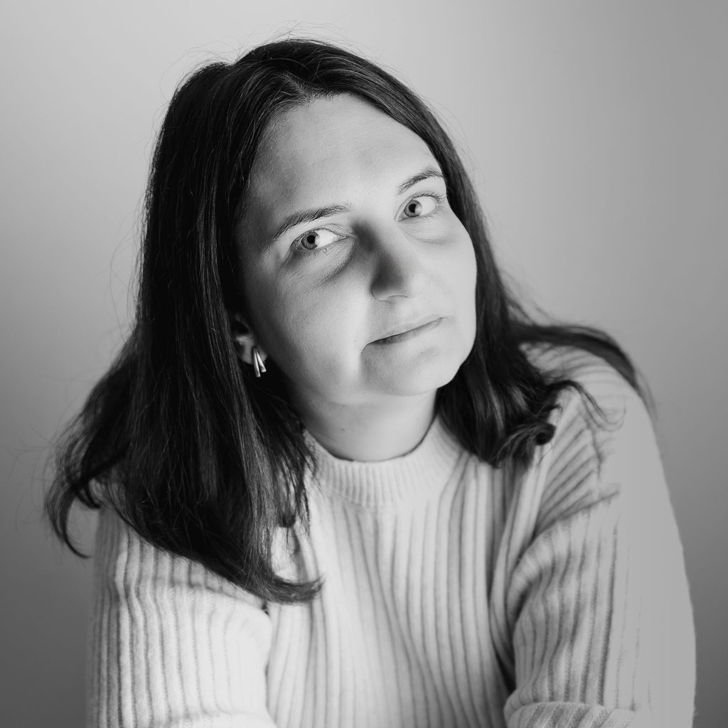 Black and white professional headshot of a woman with medium-length dark hair wearing a ribbed sweater.