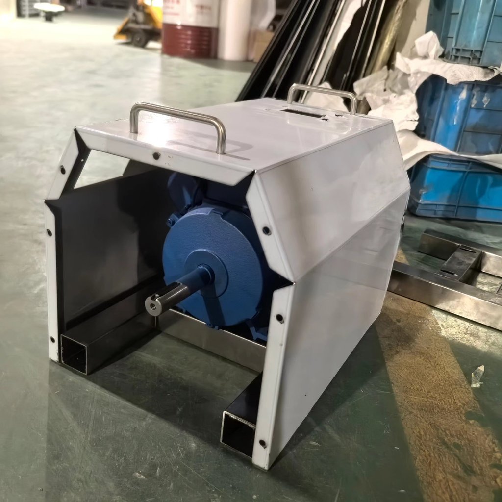 Industrial electric motor with a blue housing and metal protective cover in a factory warehouse.