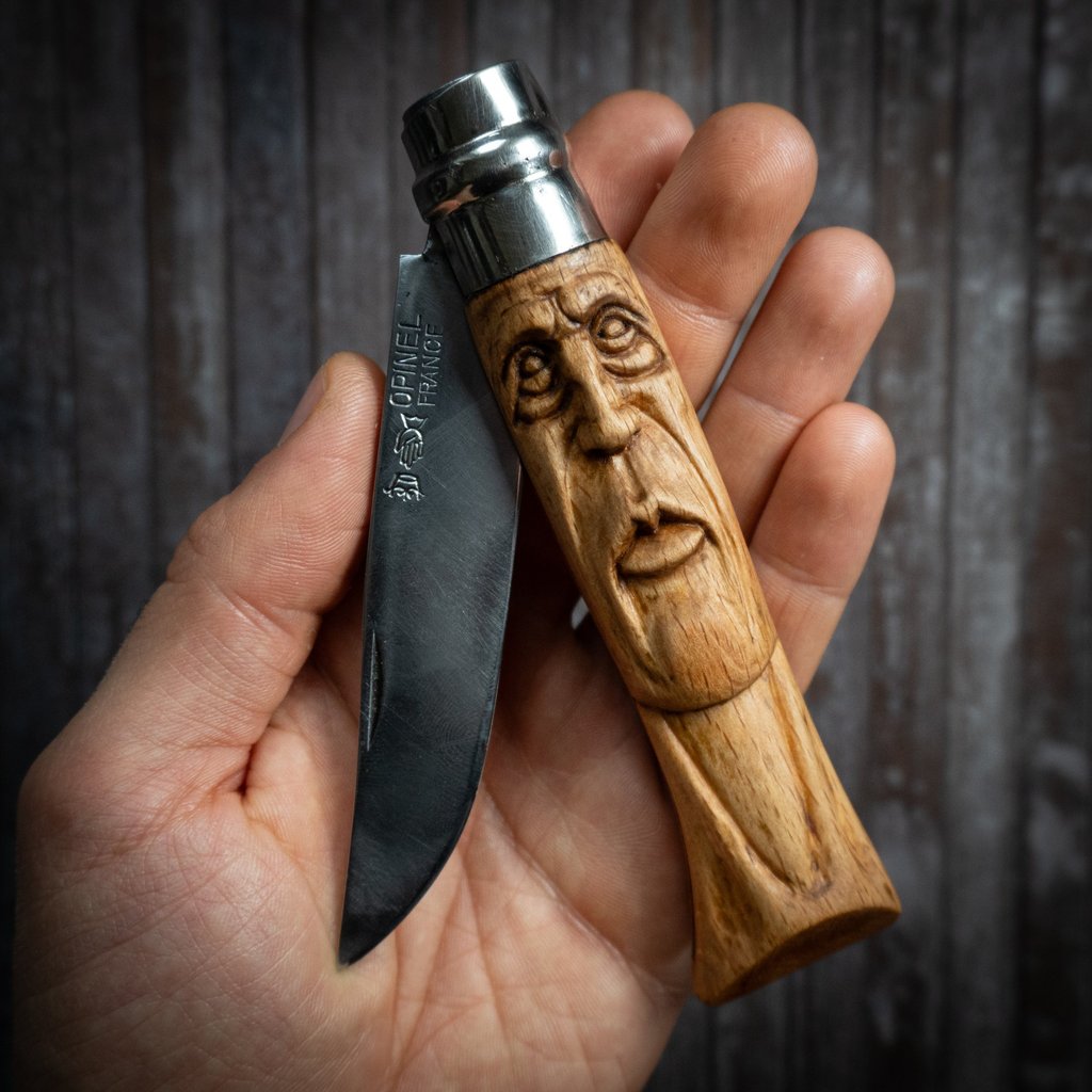 Custom hand-carved Opinel folding knife with a face sculpture on the wooden handle.