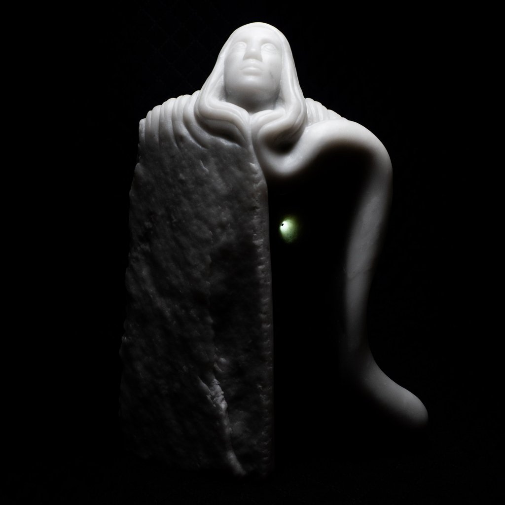 White marble sculpture of a hooded figure emerging from stone with a glowing green light.