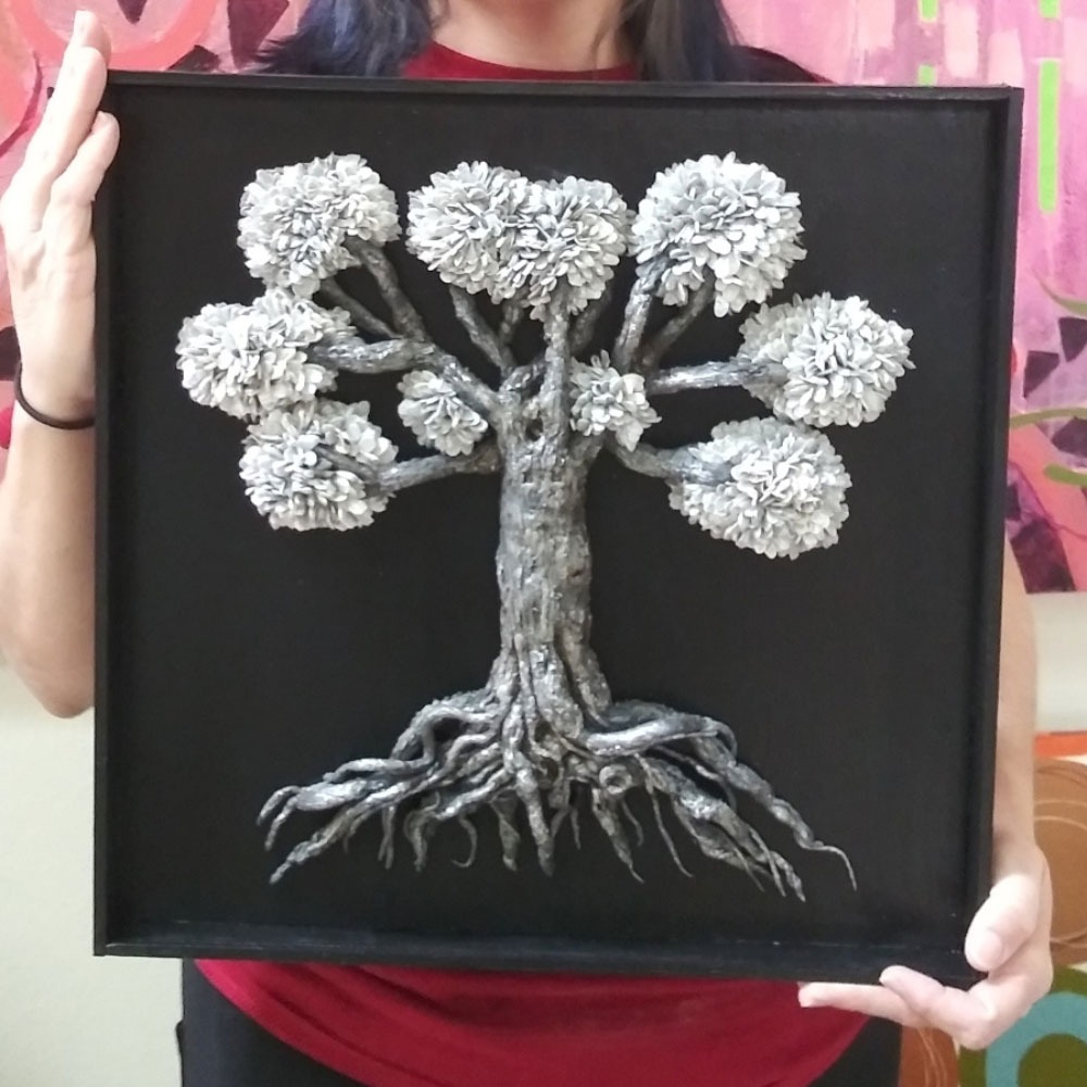 a woman holding a framed picture of a tree