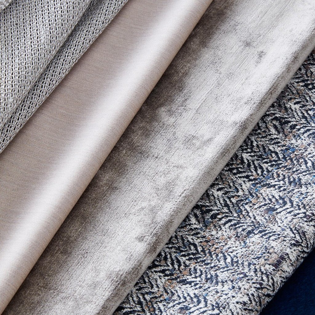 A collection of luxury upholstery fabric swatches in neutral grey, beige, velvet, and patterned textures.