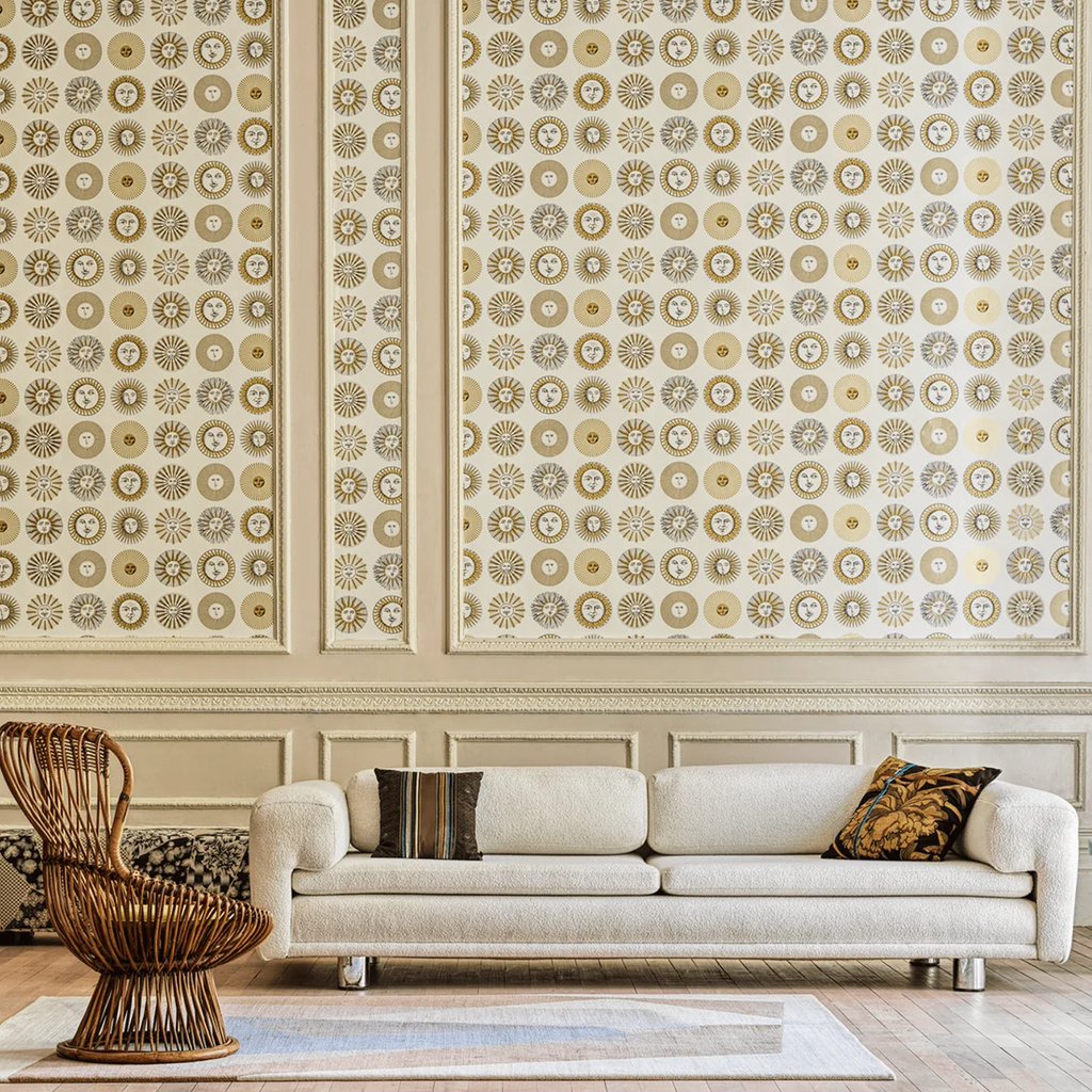 Elegant living room featuring a white boucle sofa and Fornasetti sun motif wallpaper.