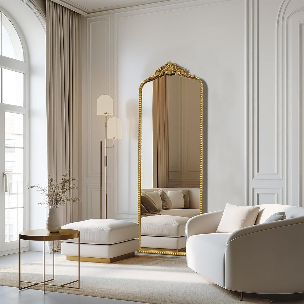 Elegant gold full length floor mirror in a luxury minimalist living room with white furniture.