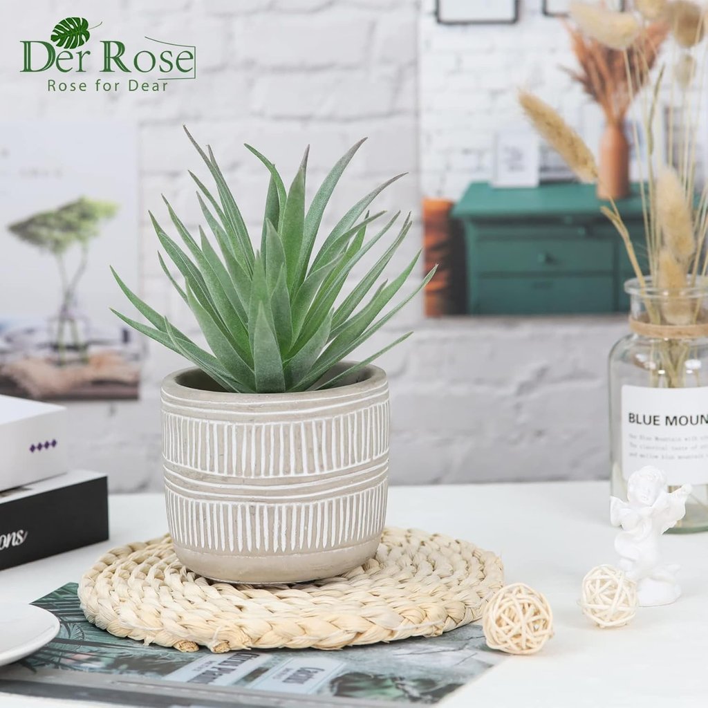 Small artificial succulent plant in a grey geometric pot on a woven coaster for home office decor.