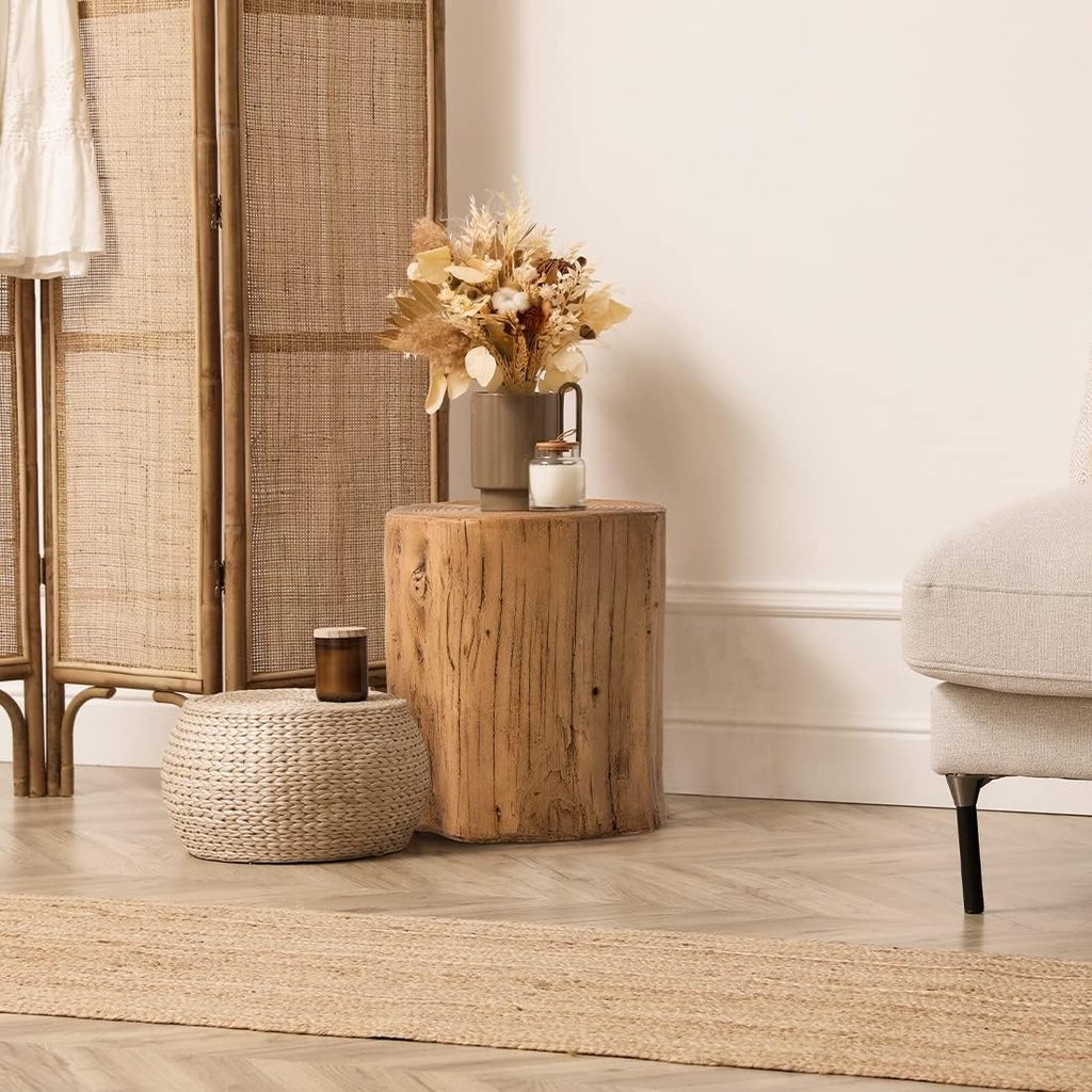 Boho living room decor featuring a natural wood stump side table, dried flowers, and a woven floor pouf.