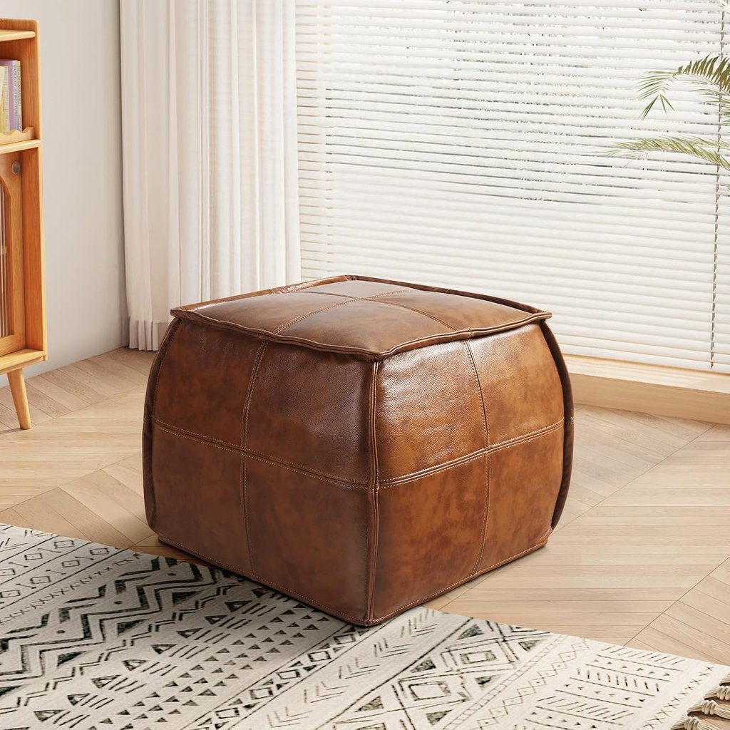 Square brown faux leather ottoman pouf stool in a modern living room with a patterned rug.