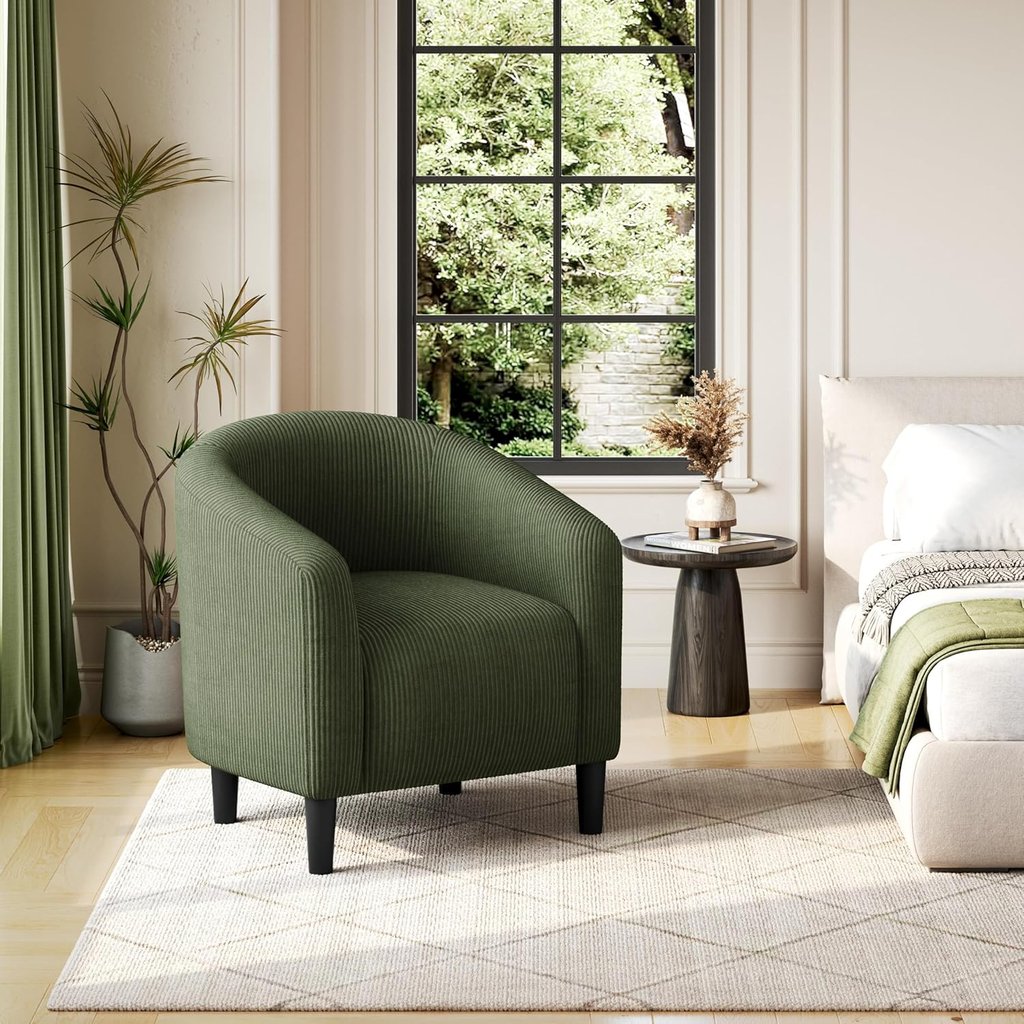 Modern green corduroy barrel chair in a bright bedroom sitting on a diamond pattern rug.