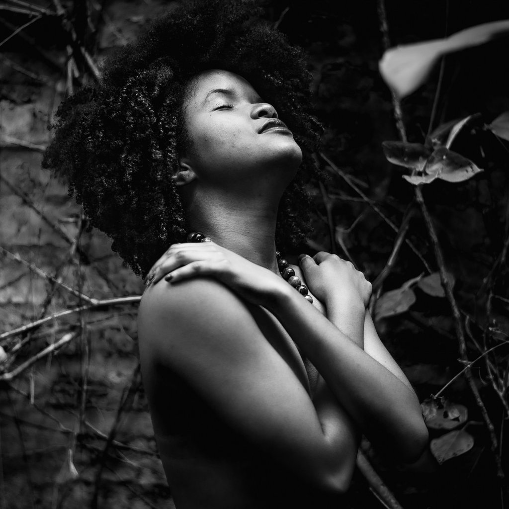Mujer afro abrazandose con los ojos cerrados, en su rostro se ve plenitud