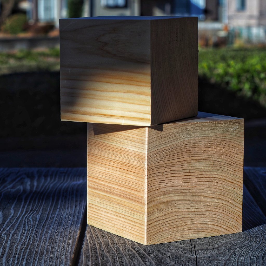 Two stacked cypress wood blocks showing natural grain patterns on a rustic timber surface.