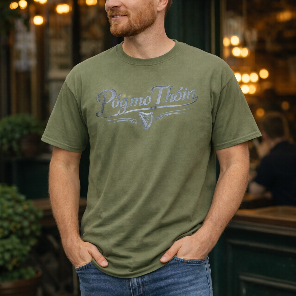 A man wearing an olive green Póg Mo Thóin t-shirt with a silver harp logo.