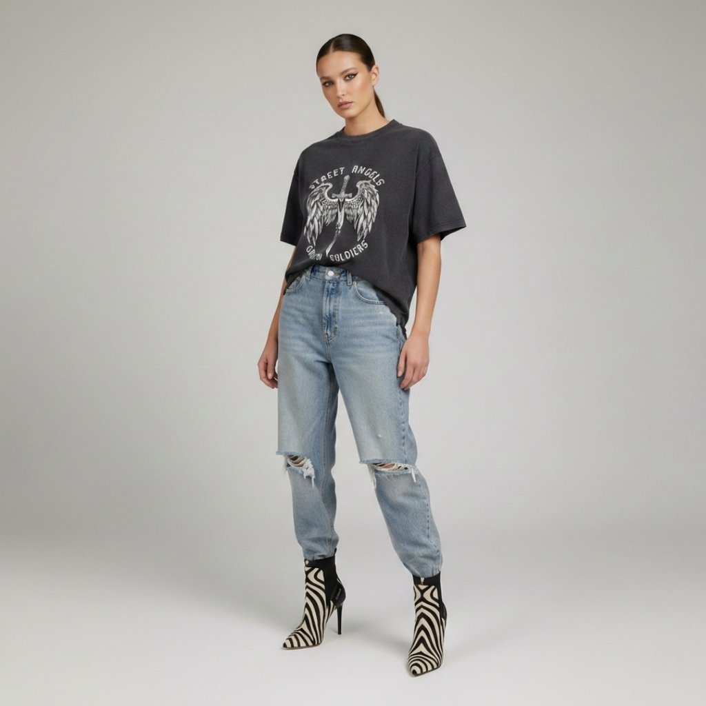 Woman wearing an oversized graphic t-shirt, distressed blue jeans, and zebra print stiletto boots.