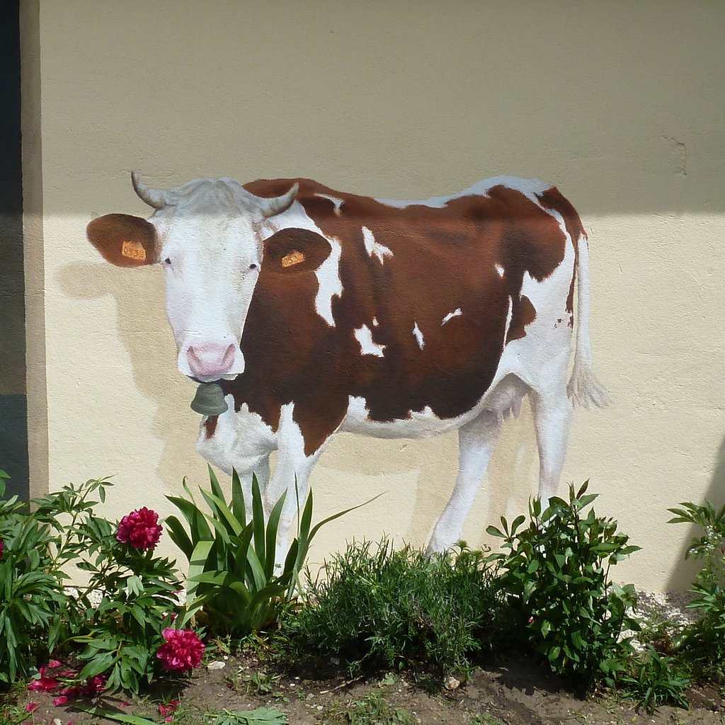 Détail d'un trompe-l'oeil sur façade: une vache Montbéliarde avec cornes et cloche. Echailla, Jura.